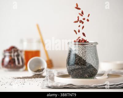 Colazione salutare concetto e idea - due colori chia pudding con materie organiche goji bacche. Il vasetto di vetro con il nero antracite e bianco latte vegano chia pu Foto Stock