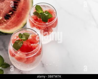 Ghiaccio di anguria con acqua frizzante o soda in bicchiere di vetro. Idea e ricetta di festa estiva, aggiungere colore e sapore per la soda o altre bevande. Spazio di copia. Foto Stock