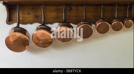 Set di pentole appese a un rack in cucina Foto Stock