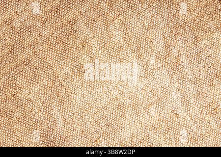 Consistenza rustica in lino. Superficie in tessuto grezzo naturale. Primo piano in materiale di fibra intrecciata. Sfondo beige neutro. Tessuto in tessuto organico lavorato a mano. Foto Stock