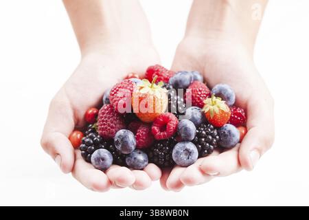 Estate frutti di bosco in mano - lampone, fragola, mora e mirtillo isolato su bianco Foto Stock