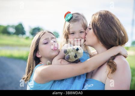 Ritratto di madre e due figlie. madre che bacia figlia Foto Stock