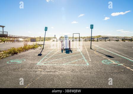 Punti di ricarica per auto elettriche in un parcheggio abbandonato lungo una spiaggia in una soleggiata mattinata d'autunno Foto Stock