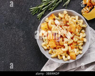 Fusilli con zucca, rosmarino e formaggio brie. Idea ricetta pasta. Cibo vegetariano. Pasta fatta in casa piatto in ciotola grigio su nero backgro concrete Foto Stock