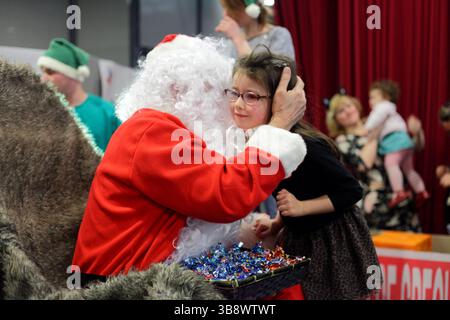 Francia Digione : le père Noël rouge embrasse une petite fille lors de l'évènement des Pères Noël verts organisé par le Secours Populaire Francais Foto Stock