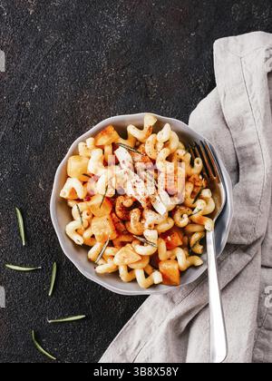Fusilli con zucca, rosmarino e formaggio brie. Idea ricetta pasta. Cibo vegetariano. Pasta fatta in casa piatto in ciotola grigio su nero backgro concrete Foto Stock