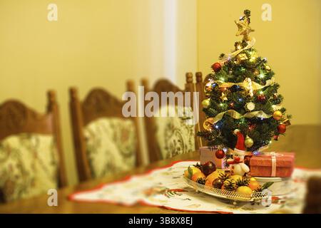 Piccolo albero di Natale con decorazioni regali e citrus sul tavolo Foto Stock
