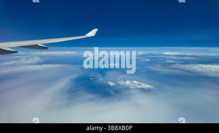 La vista dalla finestra dell'aereo alle nuvole. Ala dell'aereo sopra spesse nuvole blu e bianche. Splendida vista mozzafiato. Foto Stock