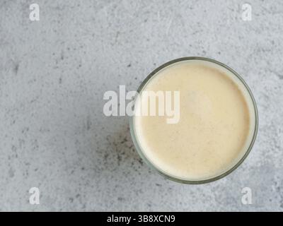 Bevanda sana latte curcuma dorato in tazza di vetro. Latte fatto in casa giallo su sfondo grigio. Latte di tè curcuma Detox. CopySpace per testo Vista superiore o f Foto Stock