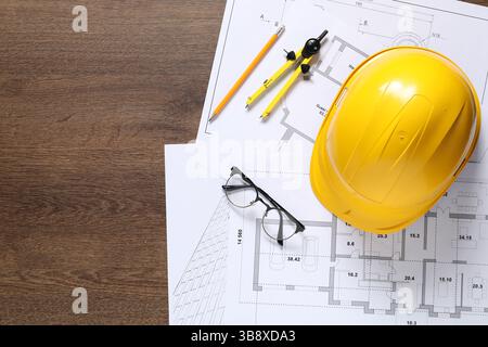 Diversi disegni architettonici, elmetto, matita, divisore e vetri su tavolo in legno, piatto. Spazio per il testo Foto Stock