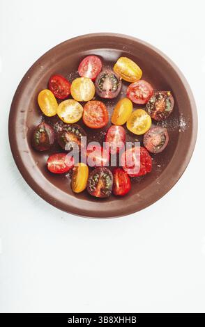Vari tipi di pomodori ciliegia sulla piastra, isolato su bianco Foto Stock