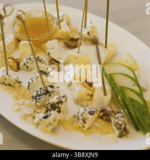 Piastra con diversi tipi di formaggi, miele, noci e pera Foto Stock