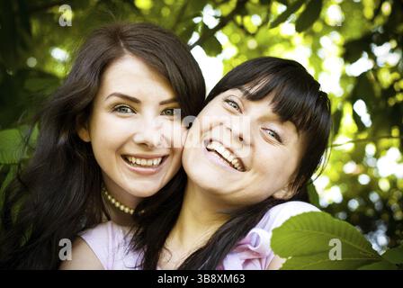 Due donne si abbracciano l'un l'altra all'aperto, volti da vicino Foto Stock