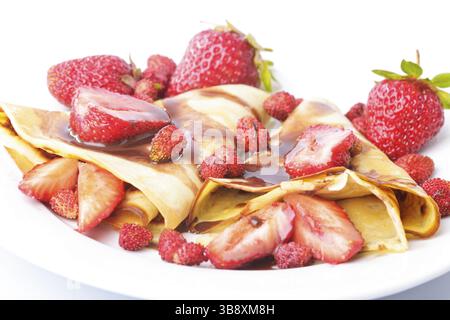 Frittelle con differenti le fragole con lo sciroppo di cioccolato su bianco Foto Stock
