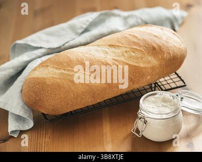 British White Bloomer o pasta di pane di Baton europeo su sfondo di legno. Pane fresco e vasetto di vetro con antipasto di pasta. Spazio di copia Foto Stock