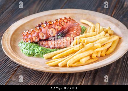 Tentacoli di polpo arrostiti serviti con spinaci cremosi e patatine fritte dorate, in stile rustico Foto Stock
