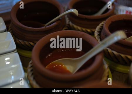 Frutti di aronia in polvere in cucchiaio di legno e vaso di argilla isolato sul bianco, vista dall'alto. Foto di alta qualità Foto Stock