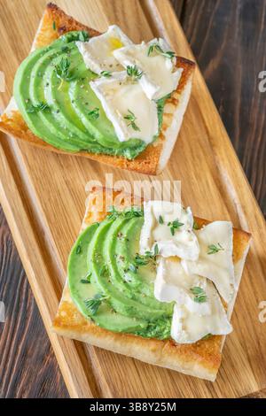 Panini tostati con ciabatta a strati di brie, avocado e spinaci cremosi, erbe aromatiche delicate Foto Stock