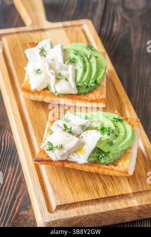 Panini tostati con ciabatta a strati di brie, avocado e spinaci cremosi, erbe aromatiche delicate Foto Stock