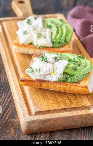 Panini tostati con ciabatta a strati di brie, avocado e spinaci cremosi, erbe aromatiche delicate Foto Stock