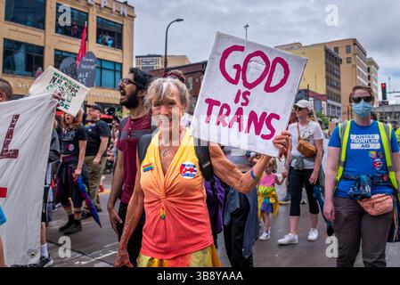 25 giugno 2023, Minneapolis, Minnesota, Stati Uniti: Un manifestante porta un segno con scritto "Dio è Trans". In risposta all'influenza aziendale e della polizia sulla celebrazione del Twin Cities Pride, la Take Back Pride Coalition organizzò la sua protesta annuale. Il gruppo marciò lungo Hennepin Avenue e terminò a Loring Park. Foto Stock
