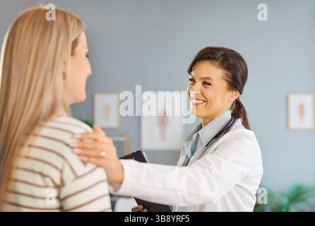 Ritratto di una donna allegra medico sostiene la giovane paziente sorridente che le mette la mano sulla spalla Foto Stock