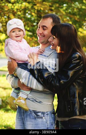 Famiglia felice all'aperto - madre, padre e figlia sorridono Foto Stock