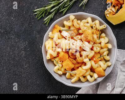 Fusilli con zucca, rosmarino e formaggio brie. Idea ricetta pasta. Cibo vegetariano. Pasta fatta in casa piatto in ciotola grigio su nero backgro concrete Foto Stock