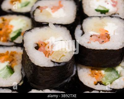 I sushi roll preparati al momento, con ingredienti vivaci, sono ben disposti. I commensali apprezzano l'atmosfera vivace mentre assaporano la loro cucina Foto Stock