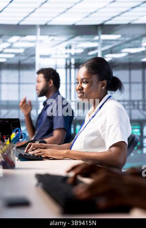 Un tecnico allegro riconfigurante la server farm per ottimizzarla in base alle esigenze di elaborazione dei dati dei clienti. Donna gioiosa che lavora per garantire il funzionamento efficiente delle apparecchiature dei data center Foto Stock