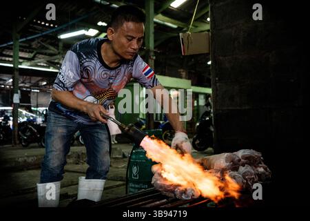 15 giugno 2023, Bangkok, Tailandia: Un venditore torce i piedi di maiale al Khlong Toey Wet Market. La vita quotidiana a Bangkok, Thailandia, come l'economia ha mostrato segni di ripresa, con il Ministero delle Finanze che ha riportato un'espansione economica del 2,6% lo scorso anno e un atteso 3,6% quest'anno, con il turismo internazionale che è un fattore chiave nella ripresa economica post-COVID. (Immagine di credito: © Matt Hunt/ZUMA Press Wire) Foto Stock