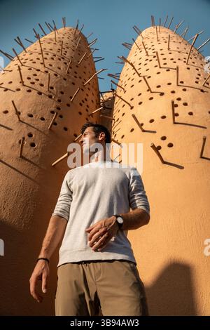 Un uomo in piedi di fronte alle tradizionali torri dei piccioni al Katara Cultural Village di Doha, Qatar Foto Stock