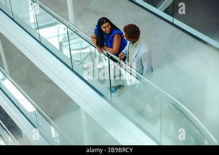 Vista dall'alto di due colleghi impegnati in una discussione su una scala moderna. La scena cattura un ambiente professionale, sottolineando la collaborazione Foto Stock