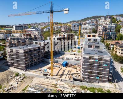 Edifici residenziali moderni in costruzione con ponteggi e gru, catturati in una giornata di sole Foto Stock