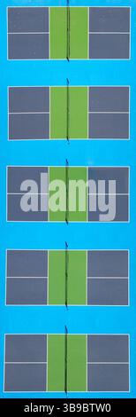 Vista aerea dall'alto verso il basso di cinque vivaci campi da pallacanestro con aree di gioco verdi e bordi blu, allineati in uno schema pulito e simmetrico e divisi Foto Stock