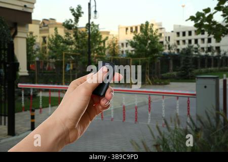 Donna che usa il telecomando per controllare la barriera del braccio all'aperto, primo piano Foto Stock