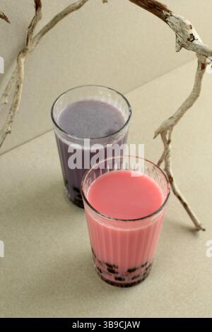 Tè al latte di bolla rosa e viola Boba Pearl su un bicchiere alto, bevanda popolare in Asia Foto Stock