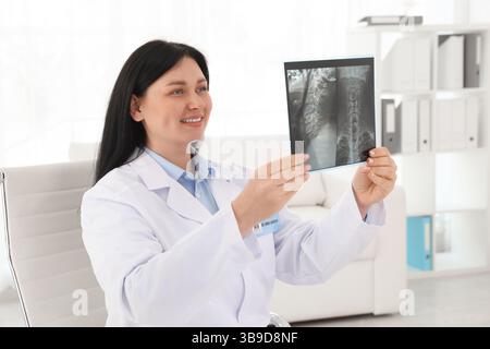 Medico sorridente che esamina la scansione RM del collo in clinica Foto Stock