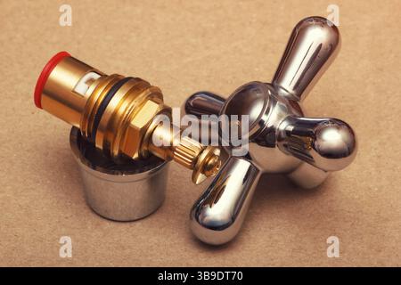Impugnatura del rubinetto cromata e cartuccia valvola in ottone. Le parti di riparazione delle tubazioni. Foto Stock