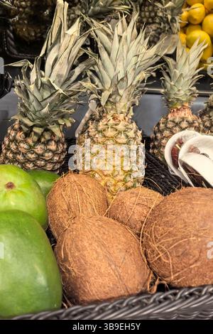 Gli ananas freschi sono fieri di affiancare le noci di cocco testurizzate in un vivace mercato. Verdi e gialli vibranti aggiungono alla vivace atmosfera di questo soleggiato fo Foto Stock