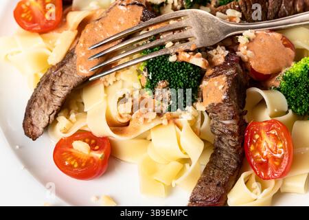 Tagliatelli con fette di bistecca su un piatto Foto Stock