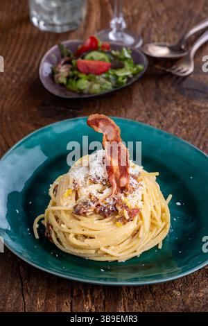 Spaghetti alla carbonara con insalata su legno Foto Stock