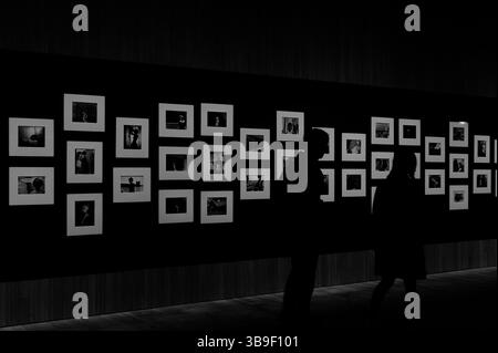 Sagome dei visitatori che osservano la mostra Masquerades di Yasumasa Morimura e Cindy Sherman al M+ Museum Foto Stock