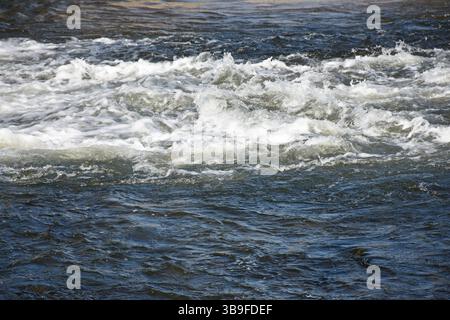 Schiumosità e spruzzi d'acqua del fiume dopo una diga Foto Stock
