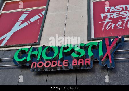 Immagine esterna di un cartello "Chopstix Noodle Bar" sotto due finestre, una con le bacchette incrociate e l'altra con testo promozionale a Liverpool, Foto Stock
