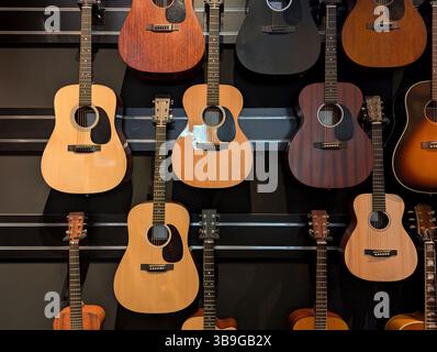 Chitarre acustiche esposte in modo ordinato su una parete, con vari modelli e finiture in legno. Perfetto per gli amanti della musica o della chitarra Foto Stock