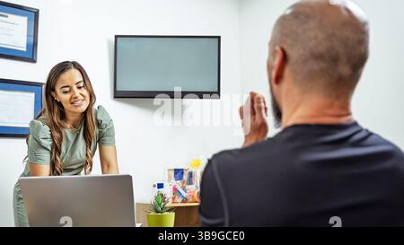 Un nutrizionista si consulta con un cliente in un ufficio moderno, favorendo un'interazione professionale. Lo spazio e' luminoso e invitante, con un'attenzione particolare Foto Stock