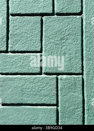 Immagine dettagliata di una parete di mattoni verdi che mostra un motivo geometrico. La superficie ruvida e il design complesso creano un interessante effetto visivo ide Foto Stock