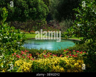 Lussuosa piscina rotonda immersa in uno splendido giardino paesaggistico, che offre un'oasi tranquilla e invitante Foto Stock