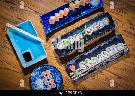 Vista dall'alto di vari sushi roll splendidamente disposti su piatti di ceramica, pronti per essere gustati Foto Stock